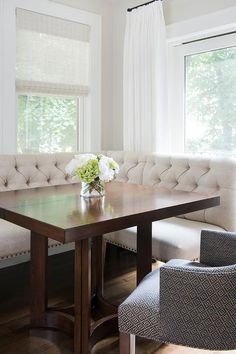 a dining room table with two chairs and a bench in front of it, next to a window