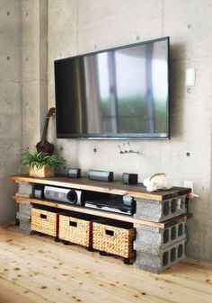 a flat screen tv mounted to the side of a wall in a living room with baskets underneath it