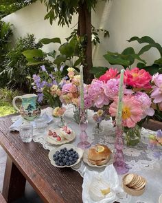 the table is set with flowers, fruit and bread on it for an afternoon tea party