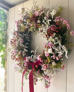 a wreath with pink and white flowers hanging on a wall next to a window sill