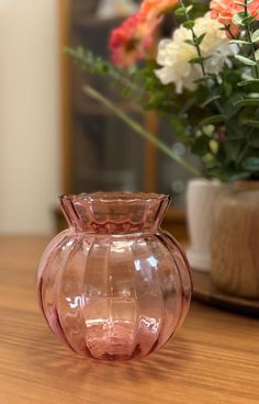 a pink vase sitting on top of a wooden table