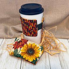 a coffee cup sitting on top of a wooden table next to a coaster and napkin