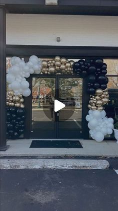 an entrance to a building decorated with balloons and golds on the front door is shown