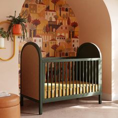 a baby crib in the corner of a room with a mural on the wall