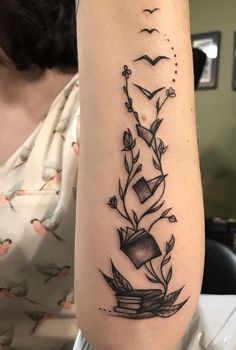 a woman with a tattoo on her arm that has flowers and books in the middle