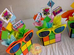 three colorful boxes with sunglasses on top of them sitting on a white sheet covered table