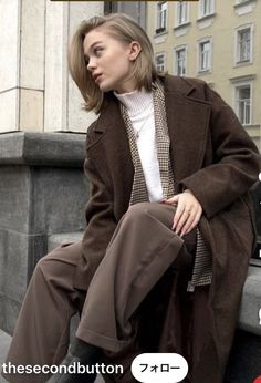 a woman sitting on the ledge of a building with her legs crossed and looking off to the side