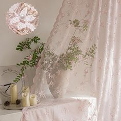 a white table topped with a vase filled with flowers next to candles and a fan