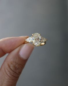 a woman's hand holding a three stone diamond ring