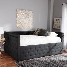 a large bed sitting on top of a wooden floor next to a white chair and table