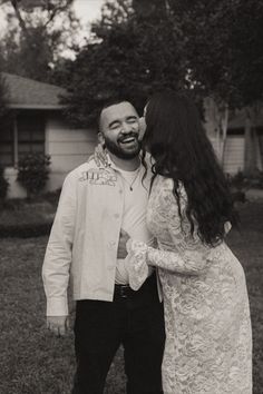 a man and woman standing next to each other in front of a house