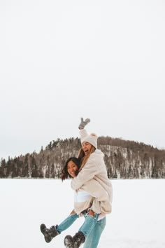 two women are playing in the snow with their feet on each other and one is holding another woman's back