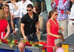 the man and woman are walking together in front of some people at a sporting event