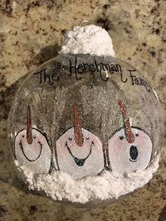 a glass ornament with three snowmen painted on it's sides and the words, the heyman family