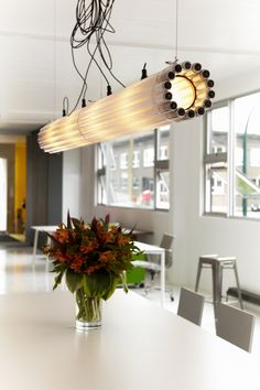 a vase with flowers sitting on top of a table next to a light fixture hanging from the ceiling