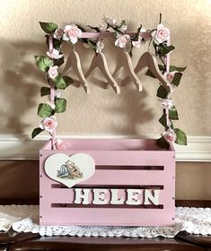 a pink wooden crate with flowers on it and the word helen written in white letters