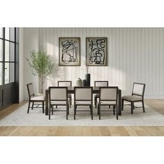 a dining room table and chairs in front of a wall with two paintings on it