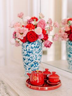 red and blue vases with flowers in them on a table next to mirror,