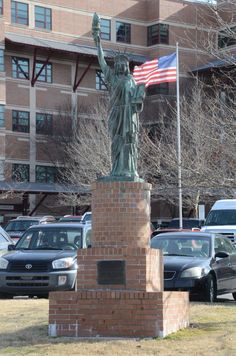 the statue of liberty is in front of a parking lot with cars parked around it