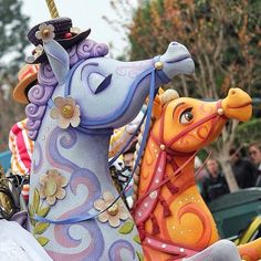 two colorful horse statues are on display in front of some other people at a parade