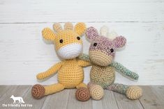 two crocheted giraffes sitting next to each other on a wooden floor