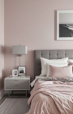 a bed with pink sheets and pillows in a bedroom next to a painting on the wall