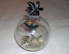 a glass ball ornament with a skeleton and bat decoration on the top, sitting on a table