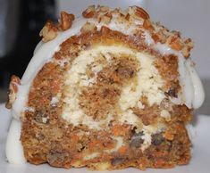 a carrot roll with white frosting and nuts on top is sitting on a plate