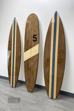 three surfboards are lined up against the wall with numbers 5 and 6 on them