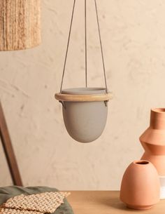 a hanging planter in the shape of a ball on a table next to two vases