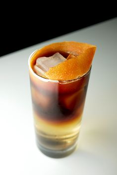 an orange slice is sticking out of the top of a tall glass filled with ice