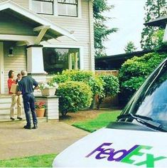 a police car parked in front of a house with two people standing outside the door