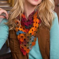 a woman is wearing a multicolored crocheted scarf