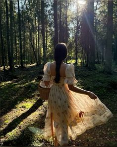 a girl in a dress walking through the woods