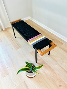 a wooden bench sitting on top of a hard wood floor next to a potted plant