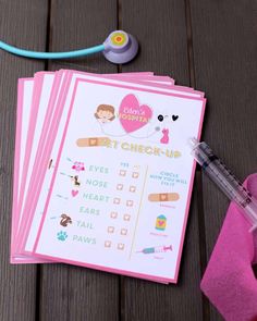 a set of pink check - up cards next to a stethoscope on a wooden table