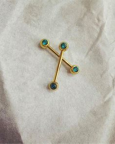 a gold cross with two blue stones on it's side sitting on a white sheet