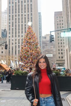 a woman standing in front of a christmas tree