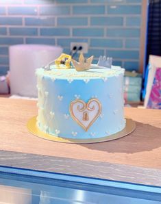 there is a blue cake with gold decorations on it and a little crown on top