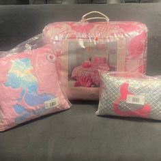 three pieces of pink and blue luggage sitting on top of a gray couch next to each other