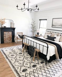 a white and black bedroom with a chandelier hanging from the ceiling, rug on the floor