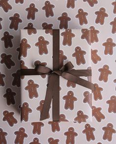 a gift wrapped in brown and white paper with ginger cookies on it's wrapper