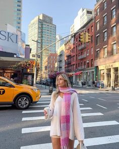 a woman standing in the middle of an intersection wearing a pink scarf and white shirt