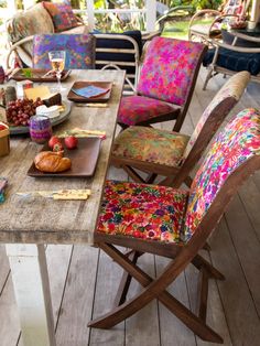 a wooden table topped with chairs covered in colorful cushions next to a picnic table filled with food and drinks