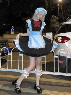 a woman dressed in an apron and dress is walking across the street with her hand on her hip