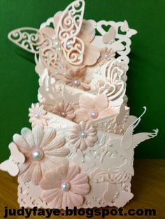 an intricately decorated card with flowers and butterflies on the front, sitting on a table