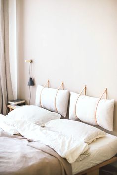 an unmade bed with four pillows on it