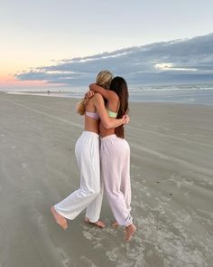 two women hugging each other on the beach