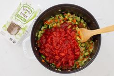 a pot filled with chopped vegetables next to a carton of brownie sticks and a wooden spoon