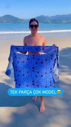 a man on the beach holding up a blue towel that says tek parca cook model